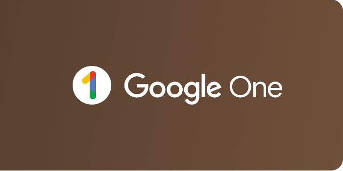 El ícono muestra el logotipo de "Google One" con un fondo marrón. A la izquierda del logotipo hay un patrón circular que contiene elementos gráficos en rojo, verde, azul y amarillo, y a la derecha está el texto "Google One".